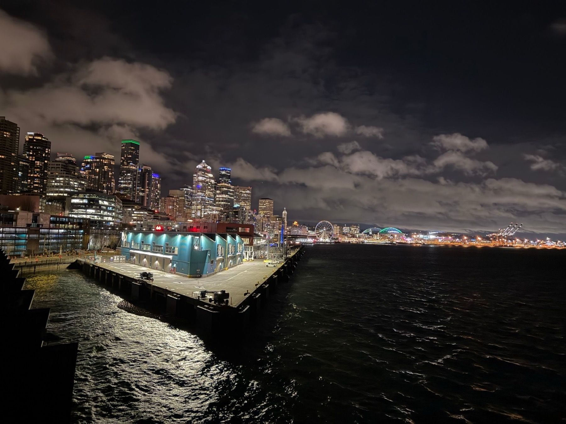 The Seattle skyline from the waterfront on a snowy, cloudy night.
